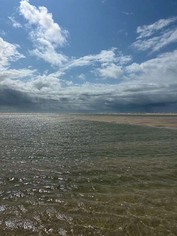 Praia de águas calmas na maré baixa, perto da casa
